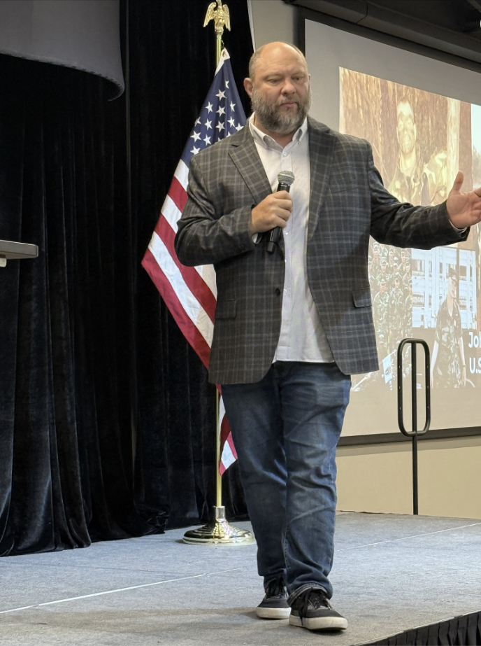 John Renken speaking on stage to a leadership audience